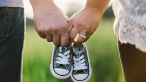 a couple holding hands and baby shoes after using parenting wisely